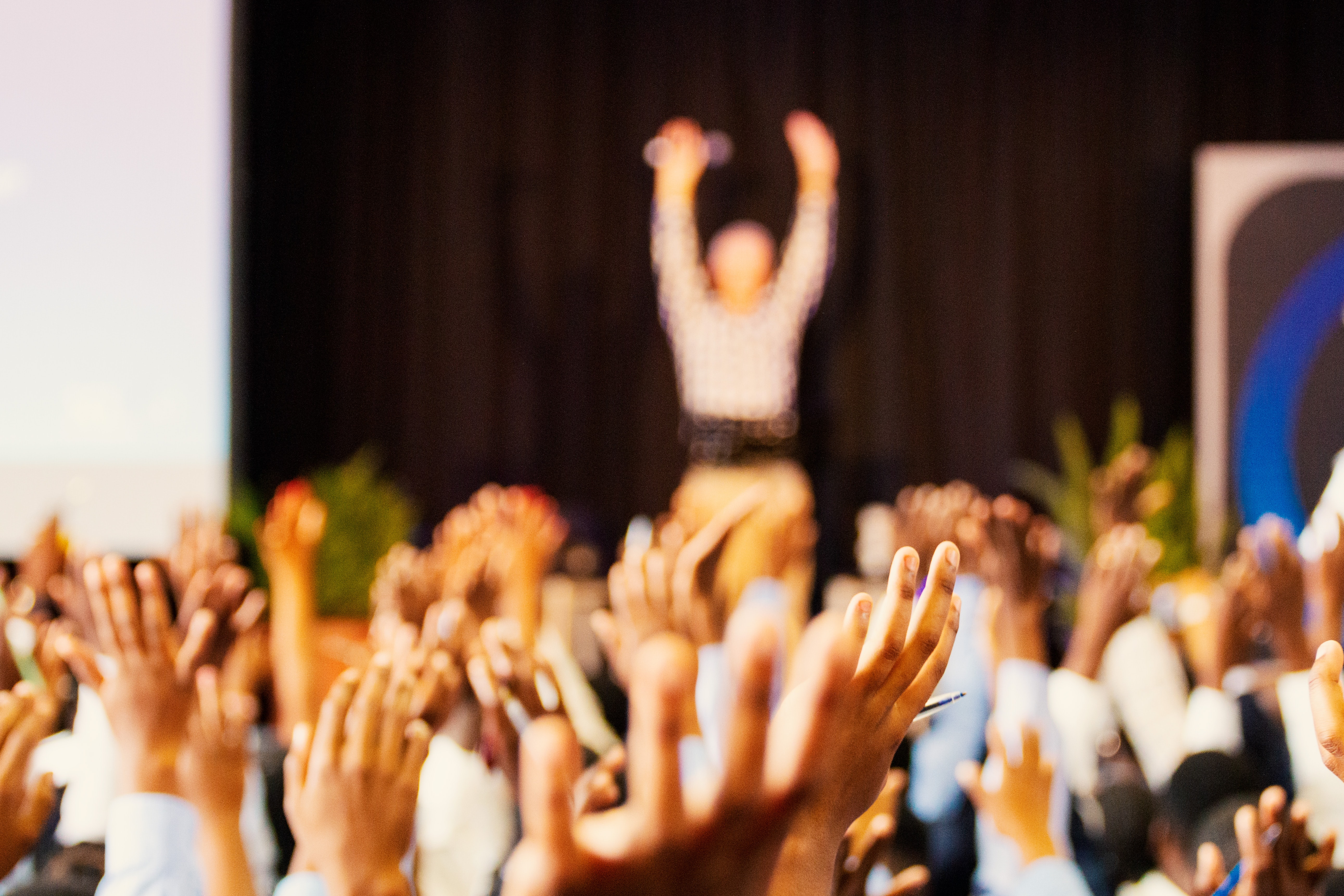 Corporate event audience raising hands and engaging with speaker | BCD Meetings & Events