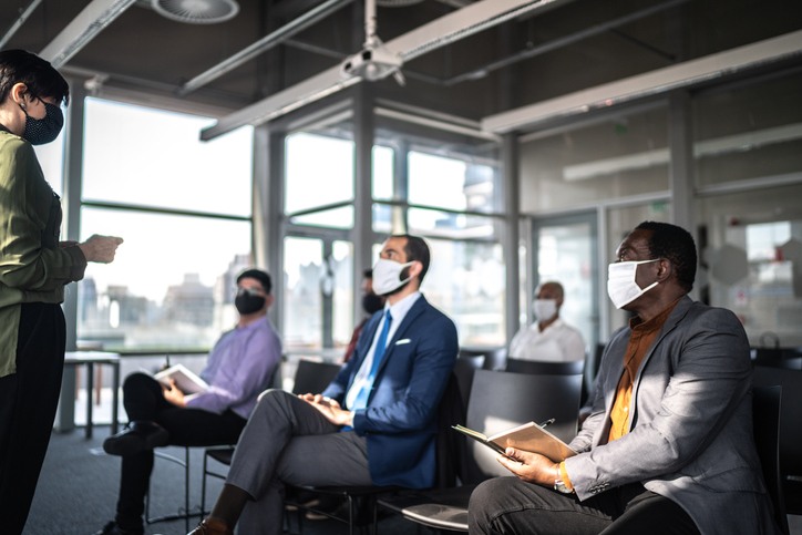Attendees sitting social distanced and wearing masks while participating in Hybrid Event presentation | Global agency, BCD Meetings & Events