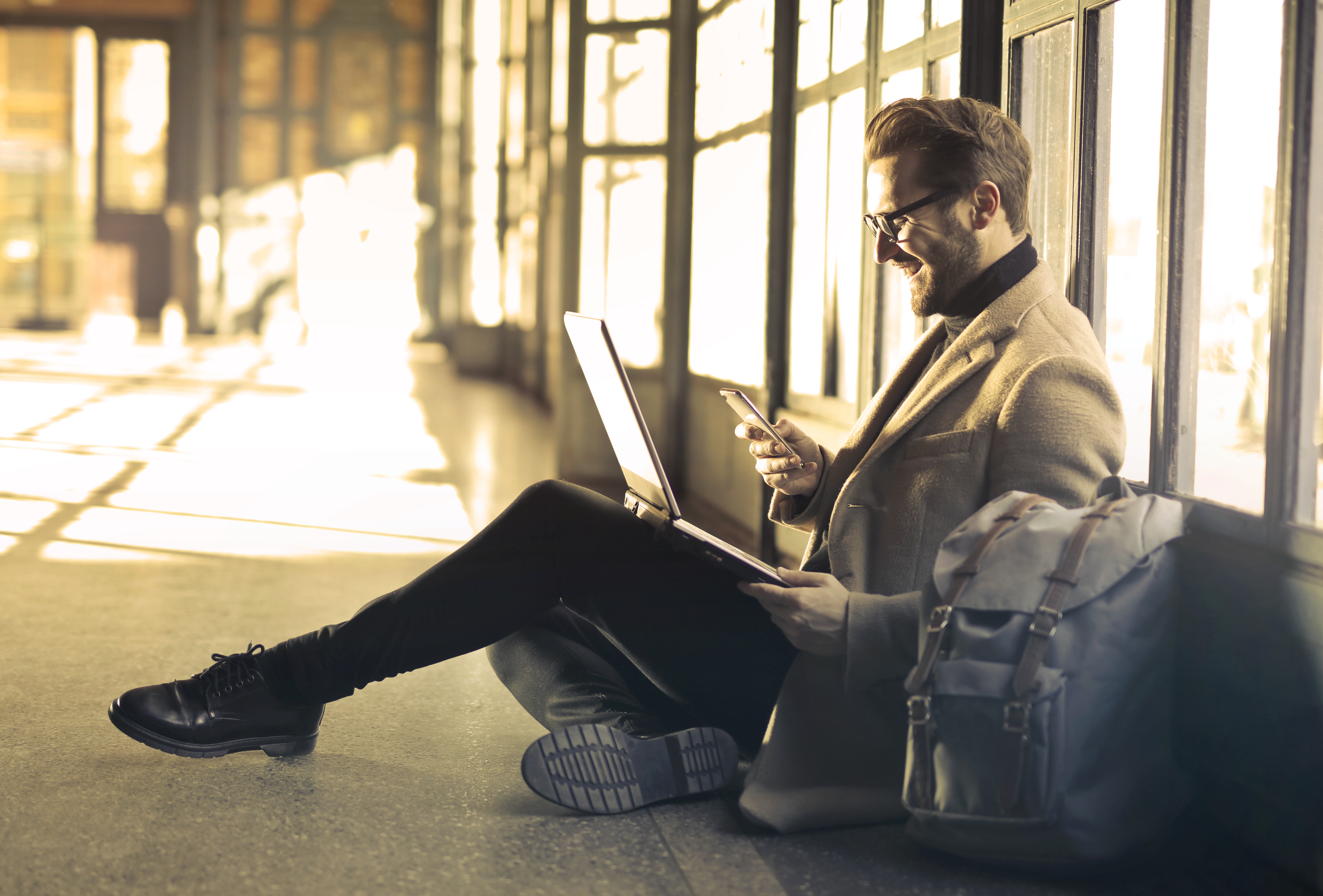 Man sitting on the floor checking email on his phone | Global Agency, BCD Meetings & Events
