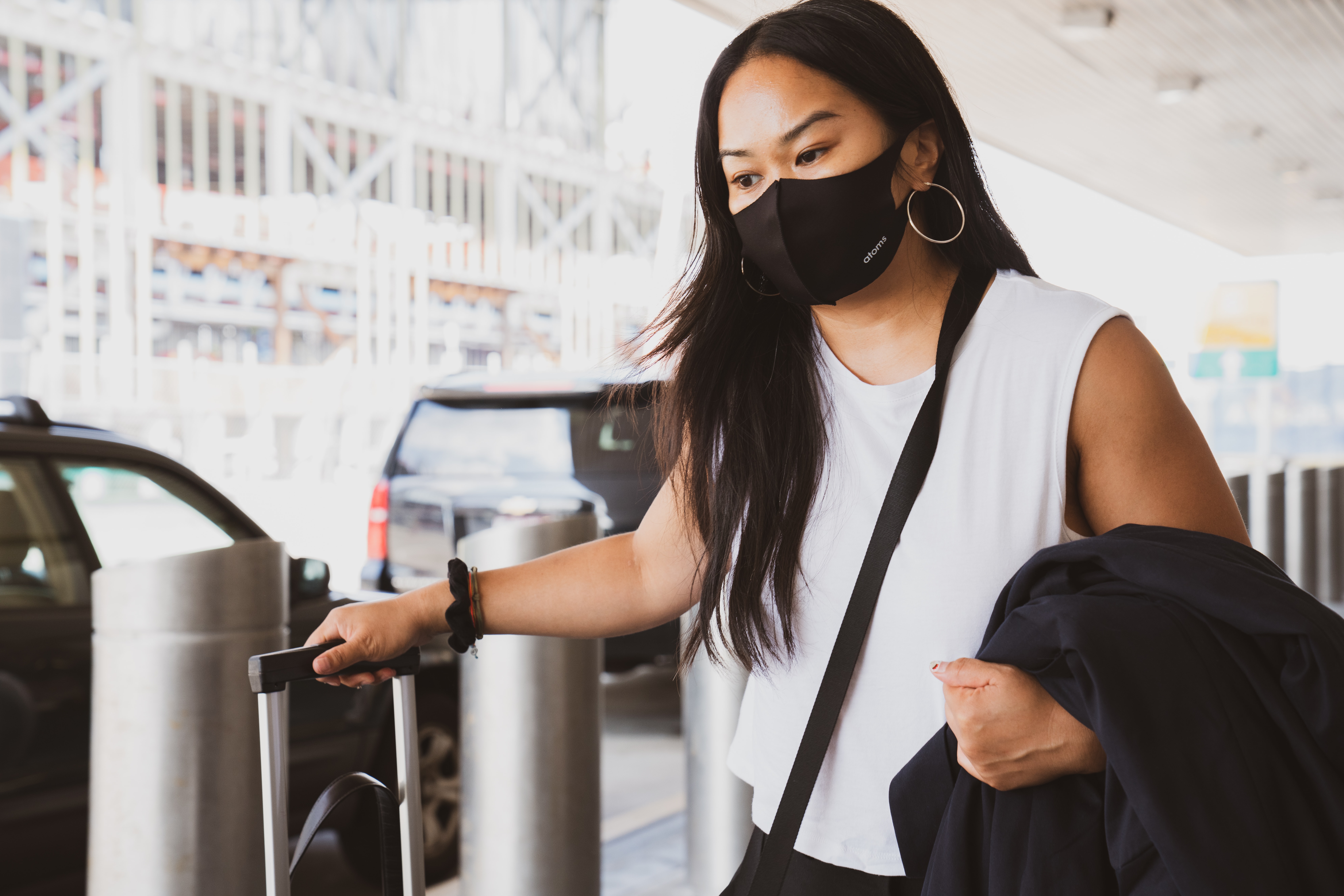 Woman wearing facemask while carrying her suitcase into the airport | Global agency, BCD Meetings & Events