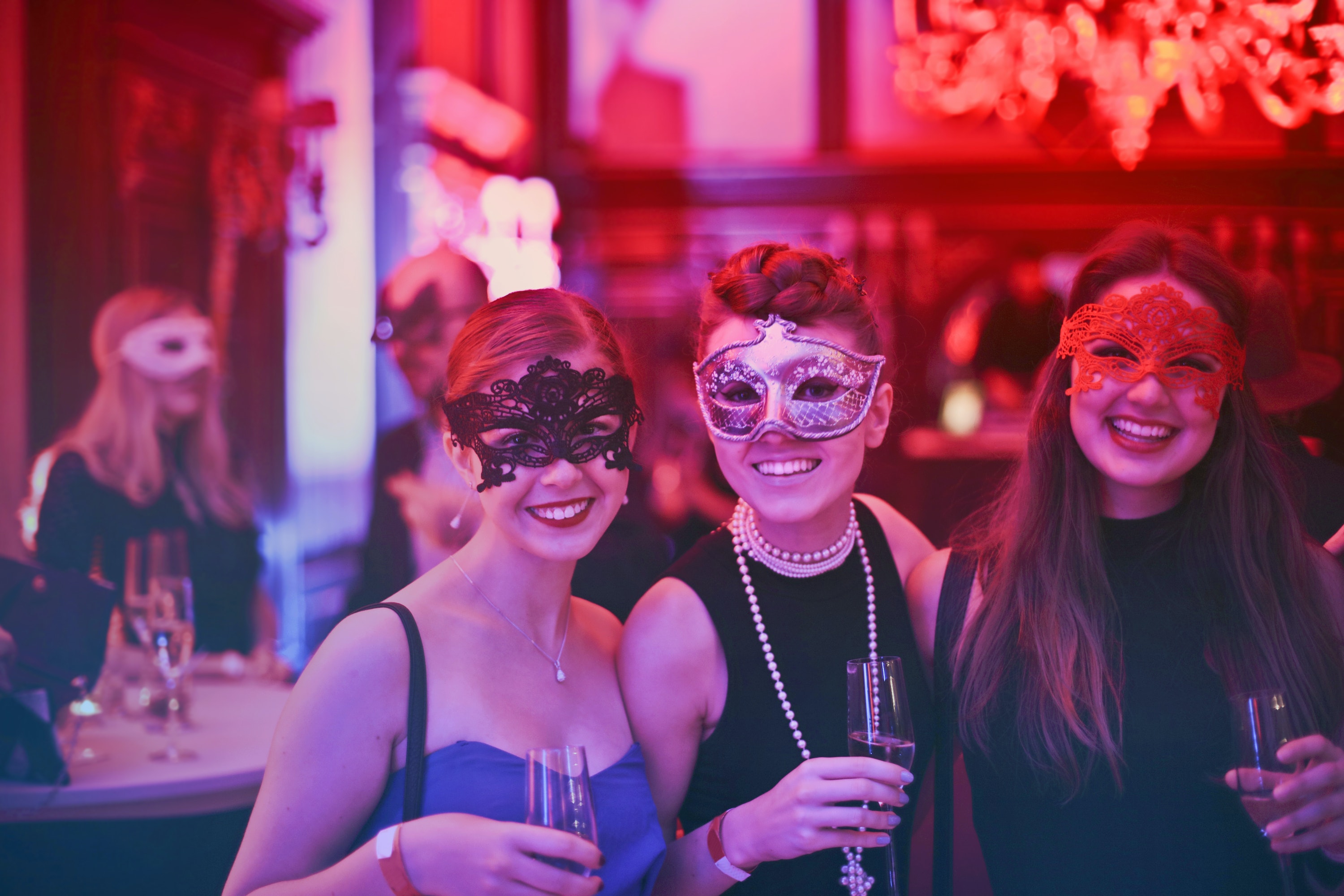Group of three female event attendees, wearing masquerade masks at corporate event | Global agency, BCD Meetings & Events