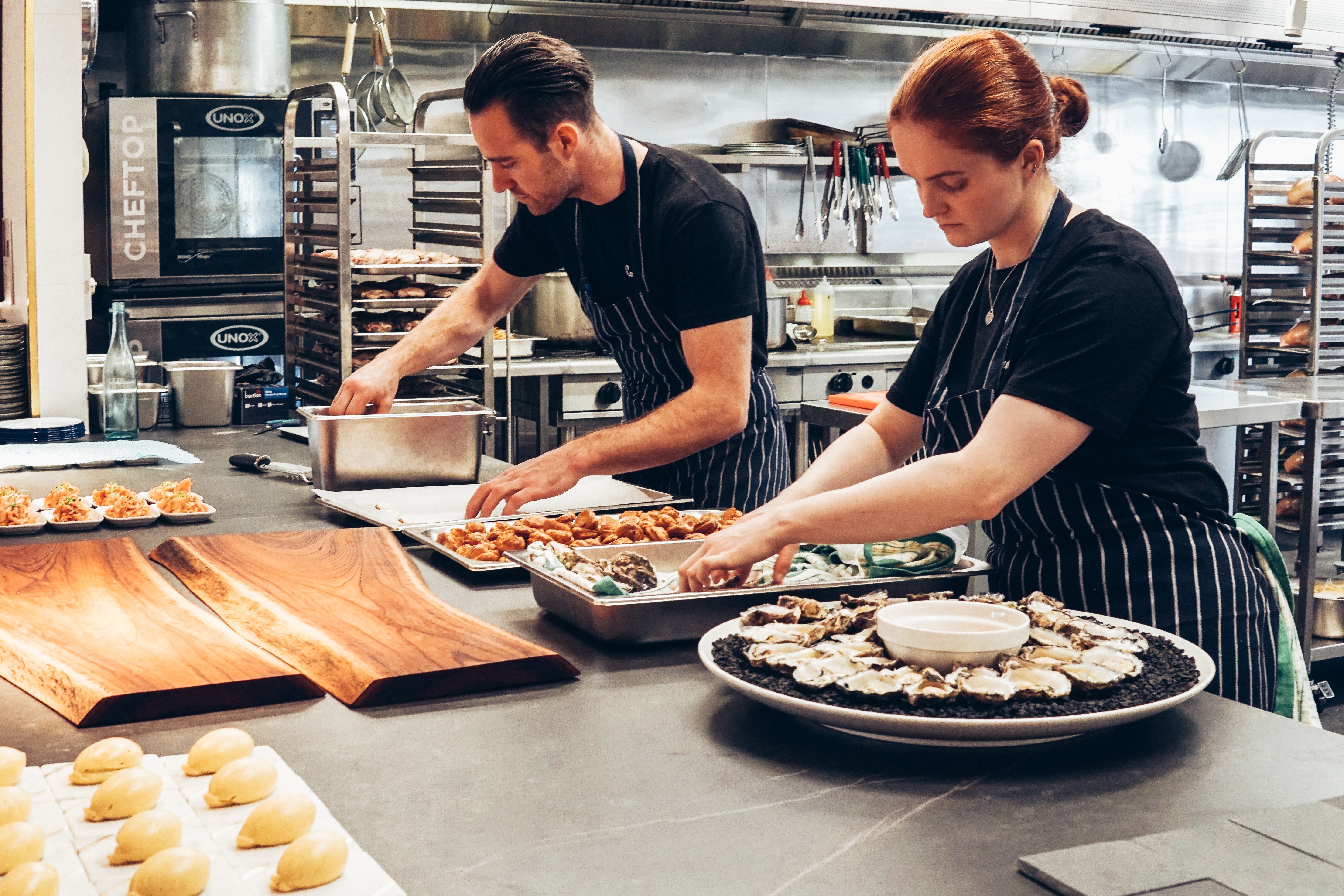 Two caterers preparing a meal for a corporate event | Global Agency. BCD Meetings & Events 