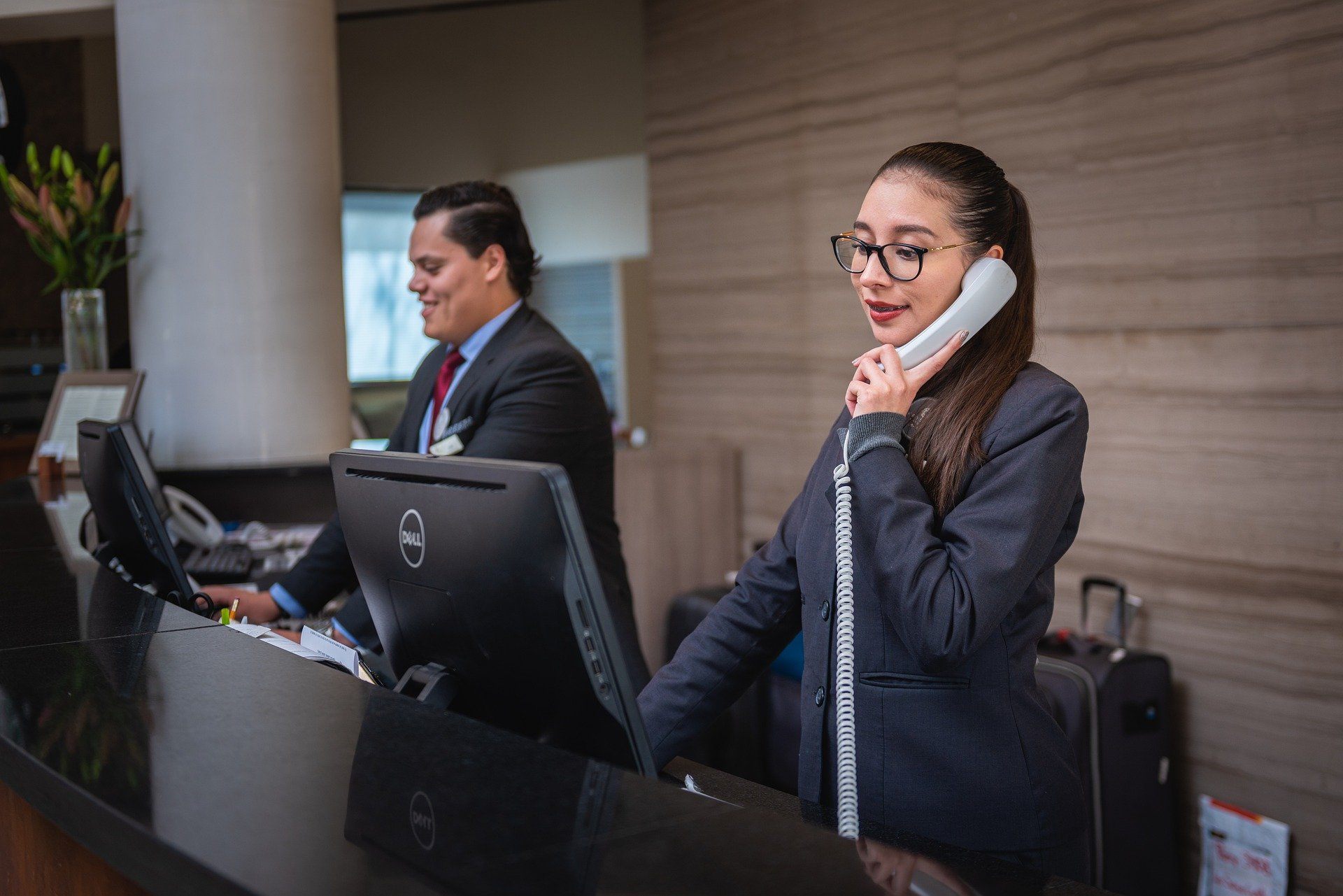 Receptionist using phone at hotel front desk | Global agency, BCD Meetings & Events