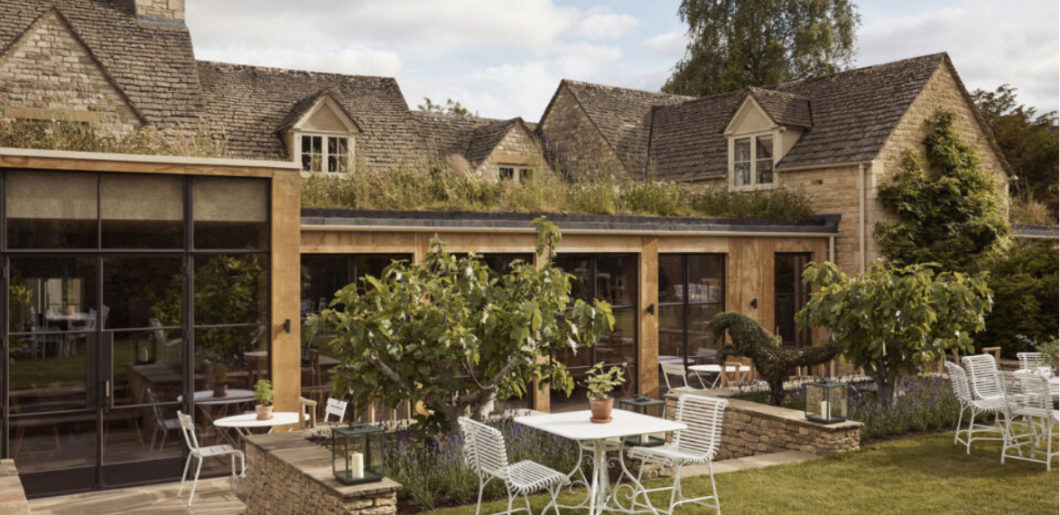 A cotswold house with tables and chairs in the garden