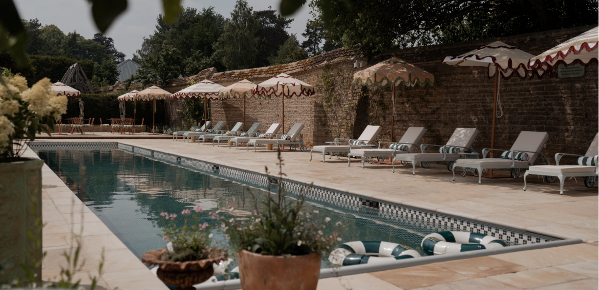 A swimming pool with sun loungers and striped parasols