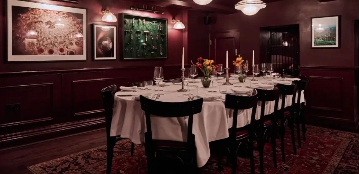 dining table with white table cloth, candles and pictures hanging on the walls.