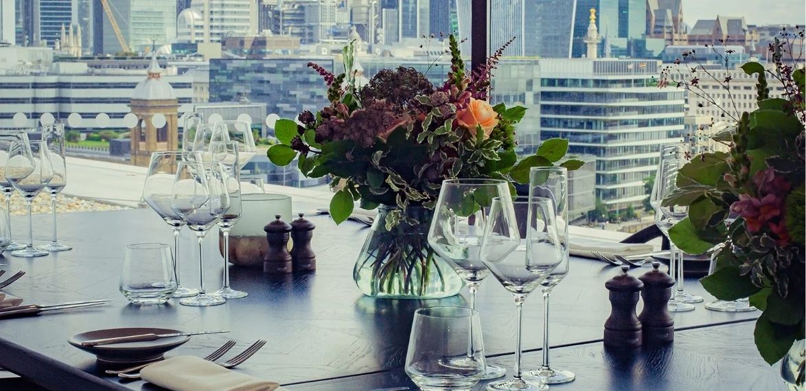 Flower and glassware on a table overlooking london skyline